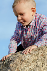 Adorable little boy climbing a rock