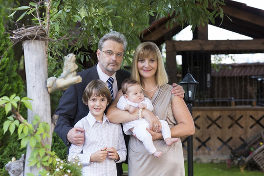 Couple in formal dress and suit with two kids in a garden