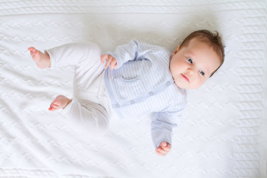 Newborn in white and blue on a white blanket