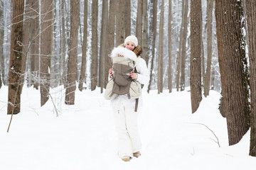 Young mother carrying baby in the forest on very snowy day