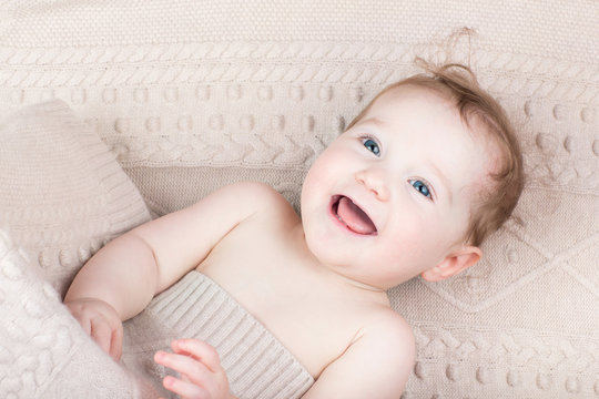 Funny laughing baby under a knitted blanket