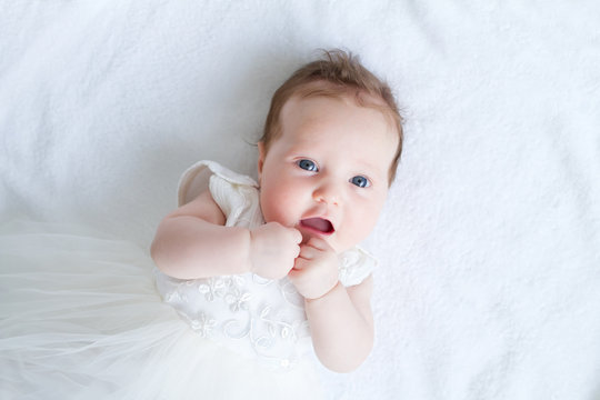 Blue eyed baby girl in a white dress