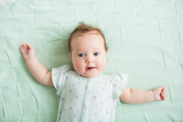 Beautiful baby girl blue eyes playing on knitted mint blanket