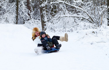 Fototapeta na wymiar Mother and son enjoying a sleigh ride on a beautiful winter day