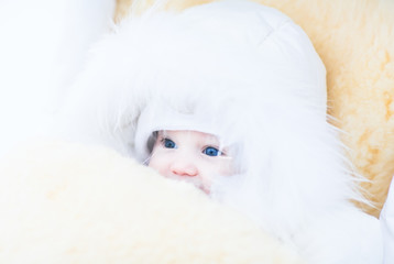 Baby girl in a white fur jacket sitting in a stroller