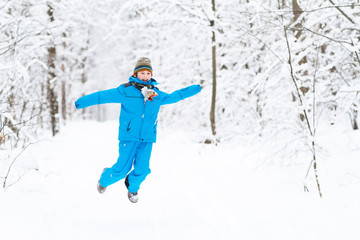 Fototapeta na wymiar Funny boy jumping in a snowy park