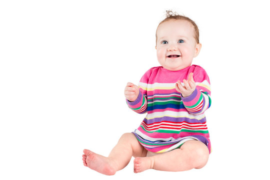 Portrait of a funny baby girl in a pink striped dress