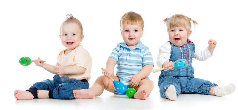 Babies playing with musical toys. Two boys and girl with maracas