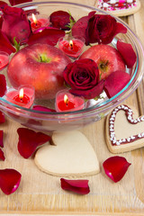 Valentine cookies, candles, rose petals and apple