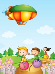 Poster Drie kinderen spelen onder een luchtschip © GraphicsRF