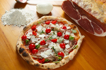 Typical Italian Pizza, ingredients in background on wood table