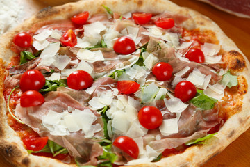 Italian Pizza, ingredients in the background on a wood table