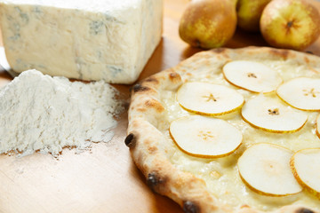 Italian Pizza, ingredients in the background on a wood table