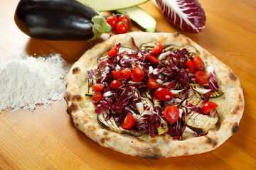 Italian Pizza, ingredients in the background on a wood table