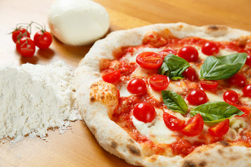 Pizza italienne typique, ingrédients en arrière-plan sur table en bois