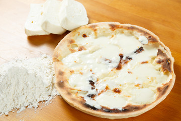 Italian Pizza, ingredients in the background on a wood table