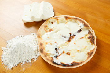 Typical Italian Pizza, ingredients in background on wood table