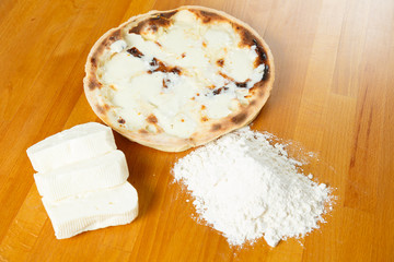 Typical Italian Pizza, ingredients in background on wood table