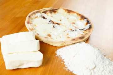Italian Pizza, ingredients in the background on a wood table