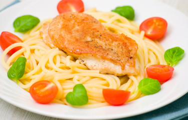 chicken breast with pasta, garnished with tomato and fresh basil