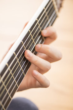 Closeup of hand and neck of acoustic guitar