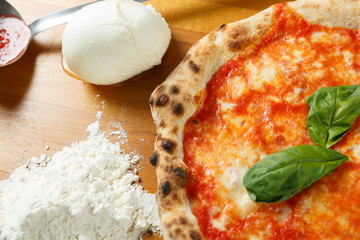 Italian Pizza, ingredients in the background on a wood table