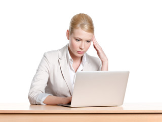 Tired young businesswoman sitting at a desk with laptop