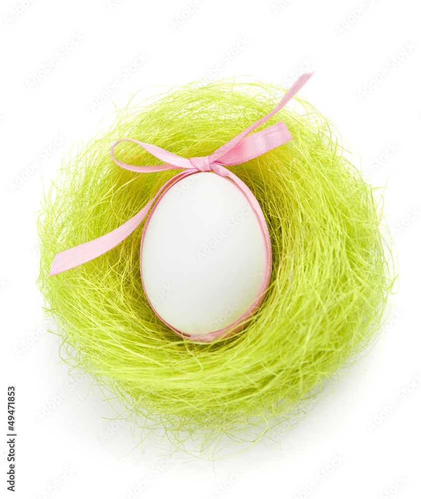 Wall mural Egg with pink bow is in the nest of green sisal fibre