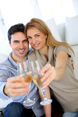 Couple holding glass of champagne towards camera