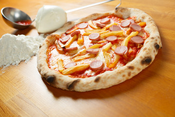 Italian Pizza, ingredients in background on a wood table