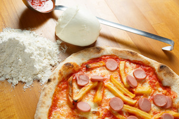 Italian Pizza, ingredients in background on a wood table