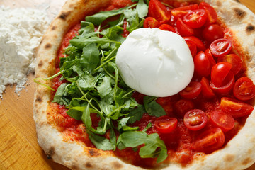 Italian Pizza, ingredients in background on a wood table