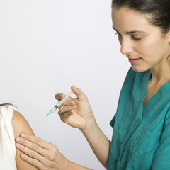 Junge Krankenschwester impft eine Patientin