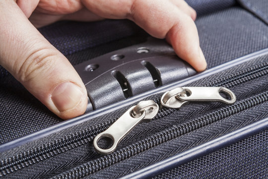 Man opens numbered lock on the suitcase zipper during packing