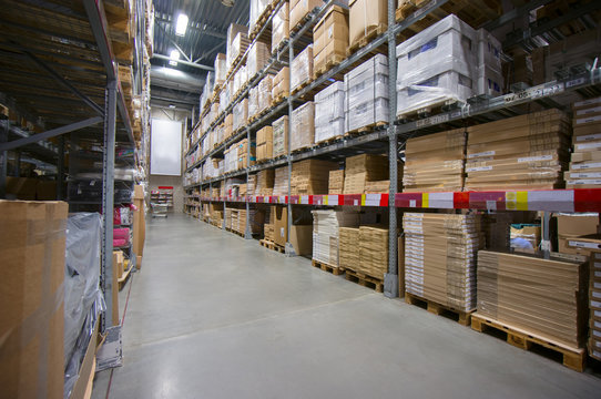 Rows of shelves with cardboard boxes on modern warehouse in stor