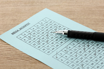 Lottery ticket and pen, on wooden background