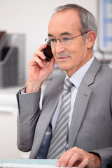 65 years old man wearing a grey suit and calling