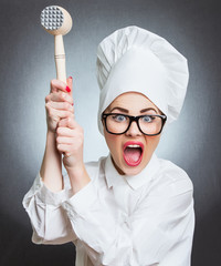 Angry woman cook trying to hit with a hammer