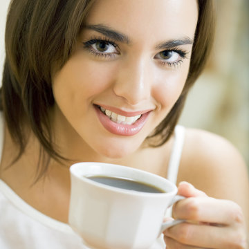 Young happy smiling woman drinking coffee
