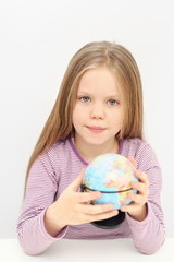 A cute girl with globe is dreaming about travels