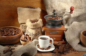 Fototapeta na wymiar Coffee grinder and cup of coffee on brown wooden background