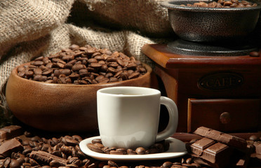 Coffee grinder and cup of coffee on burlap background
