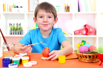 Cute little boy painting easter eggs
