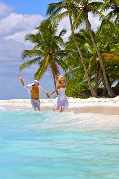 Loving couple runs on a tropical beach