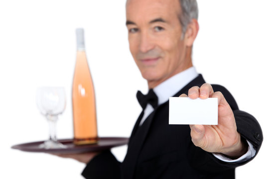 waiter carrying bottle of wine and showing his personal card