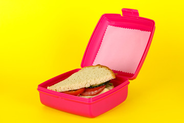 Lunch box with sandwich on yellow background