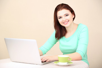 Beautiful young woman working on laptop on light background
