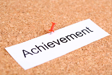 Push pin on paper with word achievement on cork board