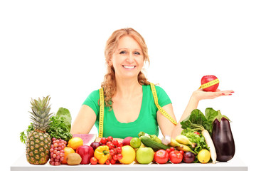 Smiling woman with fruits and vegetables holding an apple with m