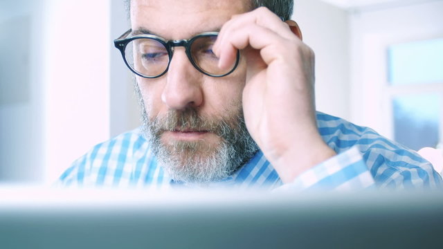 Mature Businessman with glasses working at home office - close up tracking shot 